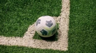 Topun yakın plan görüntüsü köşedeki beyaz çizgide duruyor ve futbol sentetik çim sahasını kauçukla işaretliyor.