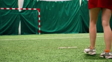 Genç bayan futbolcu kız, yeşil sentetik çimen futbolu sahası tekmeleme antrenmanında pas veriyor.