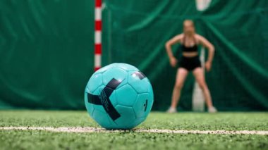 Kalecinin kalesine gol atmak için futbol sahasında topa tekme atan bir futbolcunun yakın çekimi.