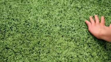 Kauçuk desenli bir futbol topunun üzerinde koşan bir elin yakın çekimi.