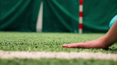 Kauçuk desenli bir futbol topunun üzerinde koşan bir elin yakın çekimi.