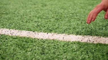 Kauçuk desenli bir futbol topunun üzerinde koşan bir elin yakın çekimi.