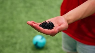Kauçuk desenli bir futbol topunu tutan elin yakın çekimi.