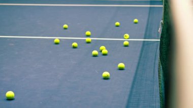 Birçok tenis topu kapalı bir mavi mahkeme oyununda internetin yanında aktif yaşam tarzı spor ekipmanları eğitimine yatar.
