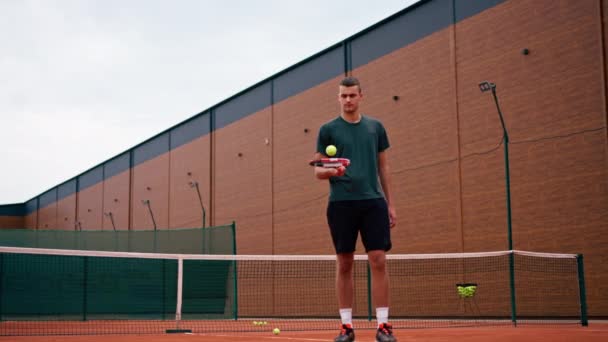若いテニス選手コーチは競技スポーツライフスタイルのために準備テニスコートにラケットでボールを打つ — ストック動画