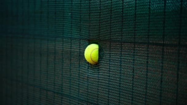 テニスボールのクローズアップは 裁判所のスポーツでプレーヤーによって強い打撃を受けた後 ネットに立ち往生 — ストック動画