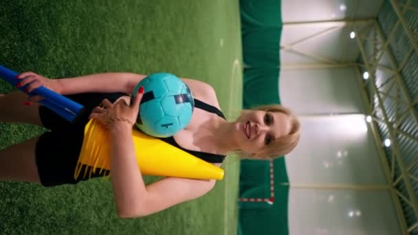 一个喜欢足球的年轻女孩在训练后手持运动器材站在球场上的垂直录像肖像 — 图库视频影像