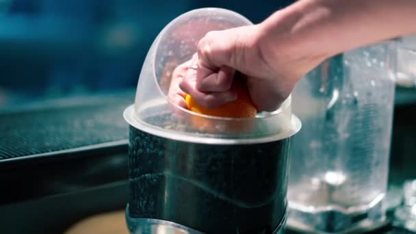 バーテンダーは 天然の新鮮な飲み物を準備するためにジューサーにオレンジの半分を置くクローズアップ — ストック動画