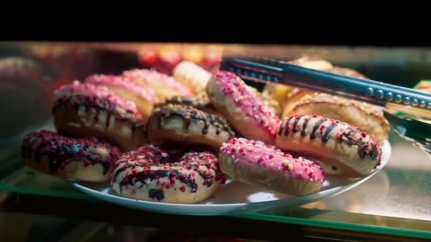 在美味而蓬松的焦糖色甜甜圈的橱窗里 用面包店或咖啡店的剃须来做特写甜点 — 图库视频影像
