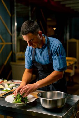 Bir İtalyan restoranının şefi profesyonel mutfakta hazırladığı yemeği süslüyor.