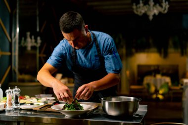 Bir İtalyan restoranının şefi profesyonel mutfakta hazırladığı yemeği süslüyor.