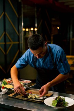 Bir İtalyan restoranının şefi profesyonel mutfakta hazırladığı yemeği süslüyor.