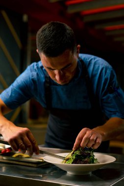 Bir İtalyan restoranının şefi profesyonel mutfakta hazırladığı yemeği süslüyor.