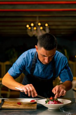 Bir İtalyan restoranının şefi profesyonel mutfakta hazırladığı yemeği süslüyor.