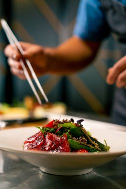 Bir İtalyan restoranının şefi profesyonel mutfakta hazırladığı yemeği süslüyor.