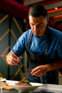 Bir İtalyan restoranının şefi profesyonel mutfakta hazırladığı yemeği süslüyor.