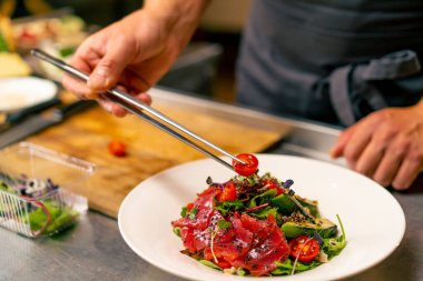 Bir İtalyan restoranının şefi profesyonel mutfakta hazırladığı yemeği süslüyor.