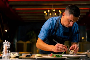 İtalyan restoranındaki profesyonel bir mutfakta biftek avokado ve domatesli bruschetta hazırlayan bir şefin yakın çekimi.