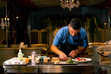 İtalyan restoranındaki profesyonel bir mutfakta biftek avokado ve domatesli bruschetta hazırlayan bir şefin yakın çekimi.