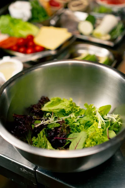İtalyan restoranının profesyonel mutfağında salata yapraklı metal bir kâsenin yakın çekimi.