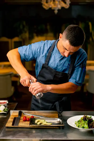 イタリアのレストランのシェフは プロのキッチンでサラダを準備しながら塩ミルを使用しています — ストック写真