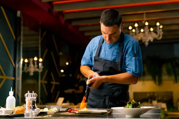 イタリアンレストランのシェフは プロのキッチンでサラダを準備しながら食材を揚げるためにガスバーナーを使用しています — ストック写真