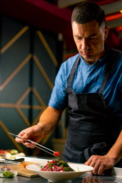 Bir İtalyan restoranının şefi profesyonel mutfakta hazırladığı yemeği süslüyor.