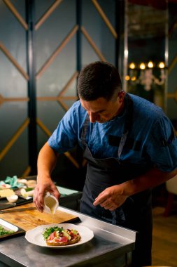 İtalyan restoranındaki profesyonel bir mutfakta biftek avokado ve domatesli bruschetta hazırlayan bir şefin yakın çekimi.