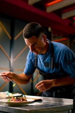 İtalyan restoranındaki profesyonel bir mutfakta biftek avokado ve domatesli bruschetta hazırlayan bir şefin yakın çekimi.