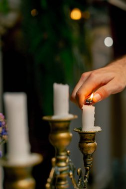 İtalyan restoranındaki bir şamdanın üzerinde mum yakmak için çakmak kullanan bir el.