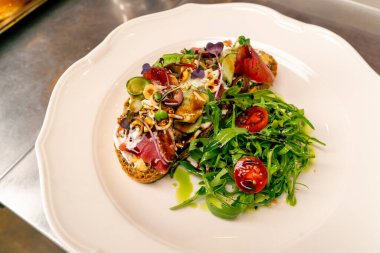 İtalyan restoranının profesyonel mutfağında pişirilmiş jambonlu ve krem peynirli bruschetta.