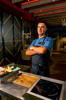 Yemek hazırlarken profesyonel bir İtalyan restoranının mutfağında duran üniformalı şefin portresi.