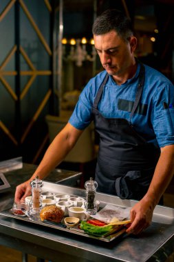 Yemek hazırlarken profesyonel bir İtalyan restoranının mutfağında duran üniformalı şefin portresi.