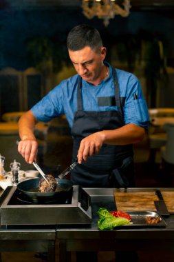 İtalyan restoranının profesyonel mutfağında köfte için köfte kızartan bir şefin yakın çekimi.