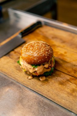 İtalyan restoranının profesyonel mutfağında pişirilen köfteli ve sebzeli ve peynirli hamburgerin yakın çekimi.