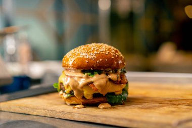 İtalyan restoranının profesyonel mutfağında pişirilen köfteli ve sebzeli ve peynirli hamburgerin yakın çekimi.