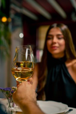 Genç bir çift İtalyan restoranında oturmuş tatlı tatlı sohbet ediyor ve buluşurken şarap içiyor.