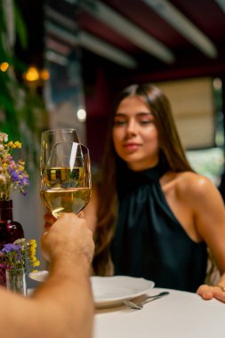 Genç bir çift İtalyan restoranında oturmuş tatlı tatlı sohbet ediyor ve buluşurken şarap içiyor.