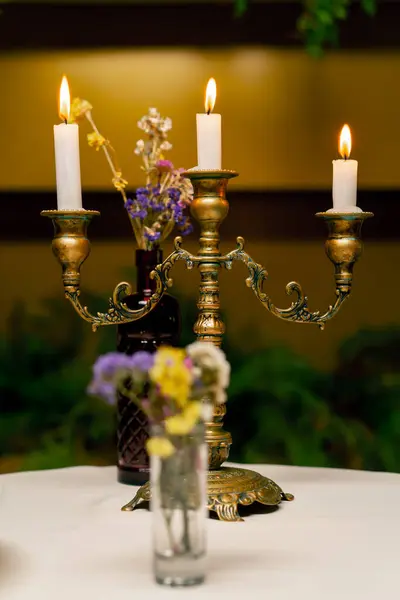 意大利餐馆里 在鲜花旁边桌子上的烛台上燃着的蜡烛的特写 — 图库照片