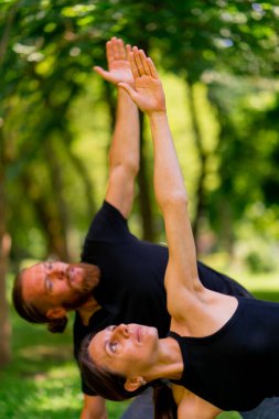 aşık çiftler ya da yoga hocası ve kadın şehir parkında egzersiz yapıyorlar.