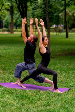 aşık çiftler ya da yoga hocası ve kadın şehir parkında egzersiz yapıyorlar.