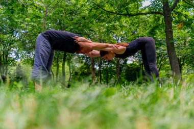 aşık çiftler ya da yoga hocası ve kadın şehir parkında egzersiz yapıyorlar.