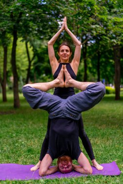 Birbirine aşık çiftler parkta yoga eğitmeninde manevi egzersizler yapıyorlar vücut germe kasları destekliyor.