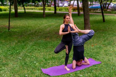 aşık çiftler ya da yoga hocası ve kadın şehir parkında egzersiz yapıyorlar.