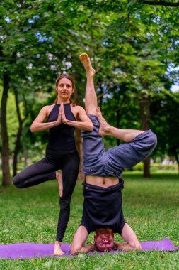 aşık çiftler ya da yoga hocası ve kadın şehir parkında egzersiz yapıyorlar.