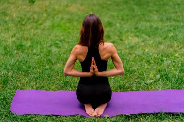 Parkta meditasyon yapan deneyimli bir kadın eğitmen. Yoga yapıyor, esneme hareketleri yapıyor ve farklı kas gruplarının bakış açılarını geliştiriyor.