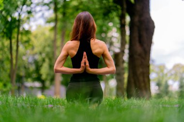 Parkta meditasyon yapan deneyimli bir kadın eğitmen. Yoga yapıyor, esneme hareketleri yapıyor ve farklı kas gruplarının bakış açılarını geliştiriyor.