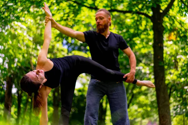 a male yoga instructor conducts a class with a woman in the park in fresh air couple exercises spiritual practices