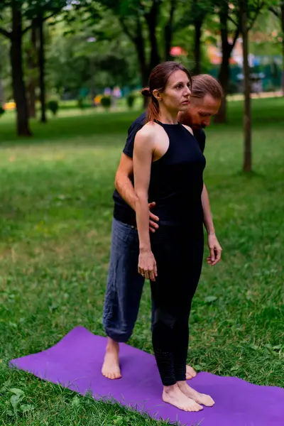 a male yoga instructor conducts a class with a woman in the park in fresh air couple exercises spiritual practices