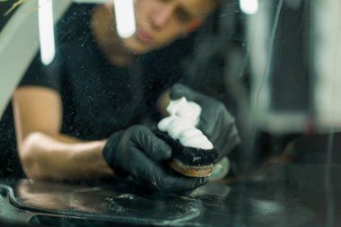 Detaylı işlemler sırasında araba yıkama işçisinin fırça ve araba kimyasalları kullanarak lüks bir arabanın gösterge tablosunu temizlemesi.